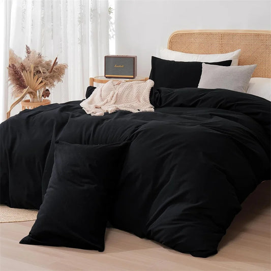 Black bedding set on a bed with decorative pillows and a wooden headboard.