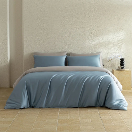 Blue bedding set on a bed in a room with a neutral wall and wooden floor.