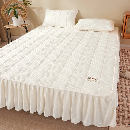 White quilted mattress cover on a bed in a bedroom setting