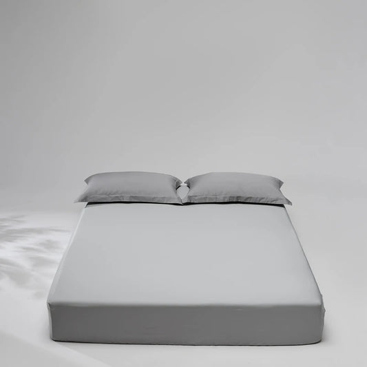 Gray mattress cover with two pillows on a plain background