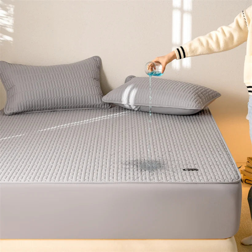 Person pouring water onto a gray quilted mattress cover on a bed.