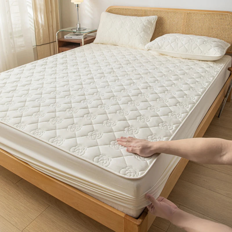 Person adjusting a white mattress pad on a wooden bed in a bedroom.