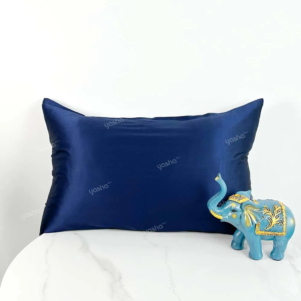 Navy satin pillowcase with 'yasha' branding on a white background, accompanied by a decorative elephant figurine.