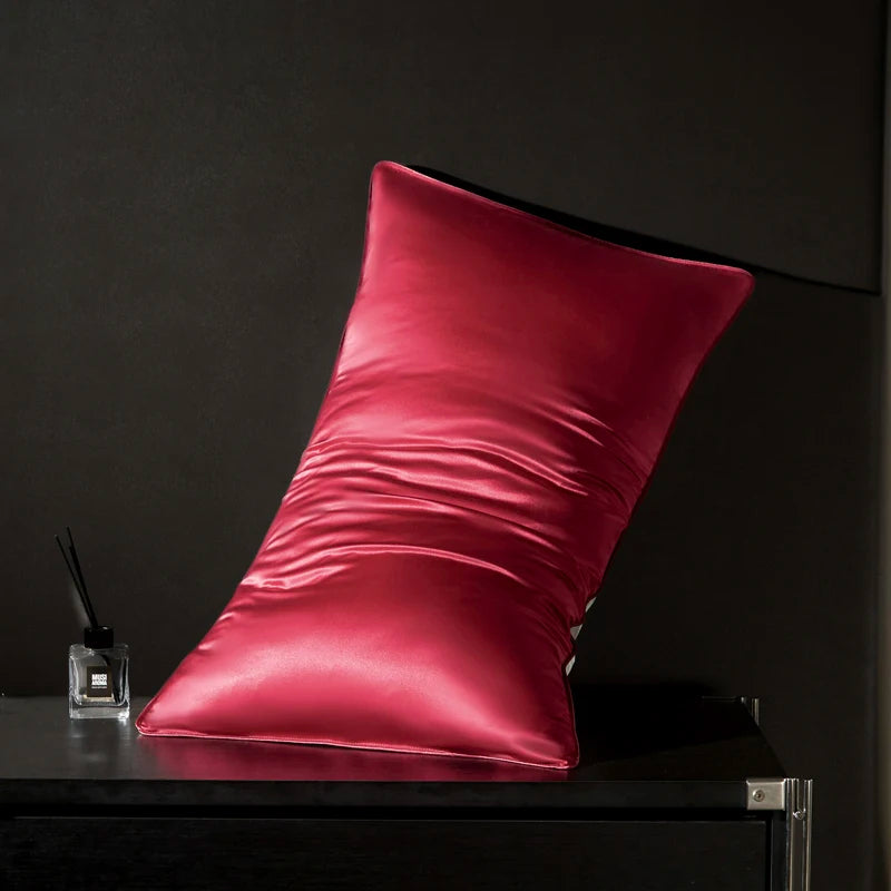 Pink satin pillow on a dark surface with a dark background