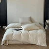 White comforter on a bed with a minimal background