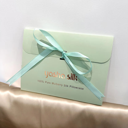 Light green pillowcase with a blue ribbon and 'Yasha Silk' branding on a white background.