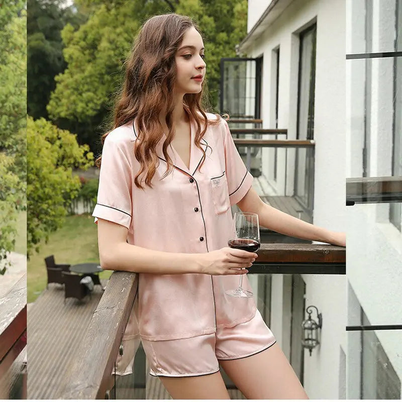 Woman in pink pajama set holding a glass of wine on a balcony.