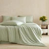 Light green blanket on a bed with a blurred background