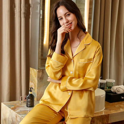 Woman wearing yellow satin pajamas sitting on a vanity table.