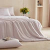 Light-colored bedding set on a bed with pillows in a softly lit bedroom.