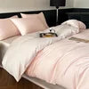 Bed with pink bedding and a nightstand in the background