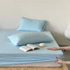Blue bed sheets on a bed with a white pillow and light blue blanket.