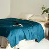 Blue blanket on a bed with a blurred background