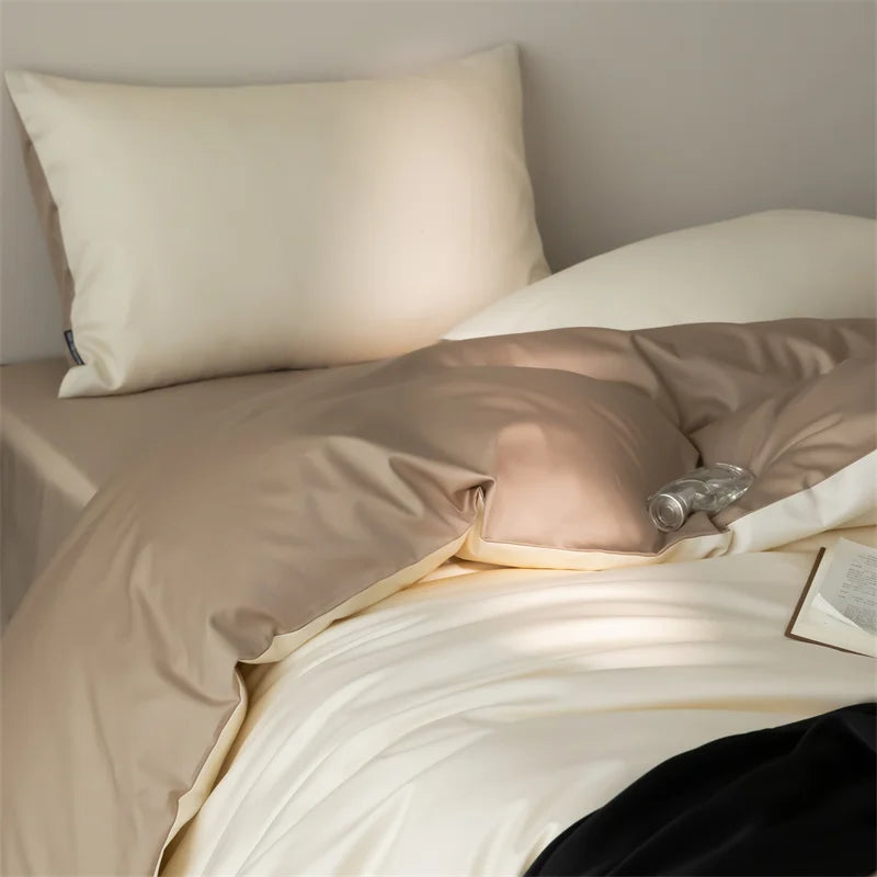 Beige bedding set with pillows and a bottle on a bed.