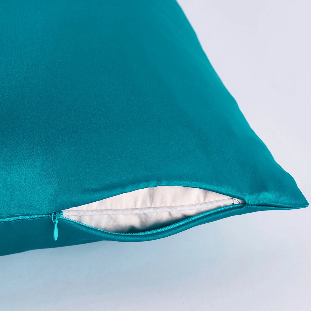Teal pillow with zipper on a light blue background