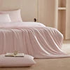 White bed with pink blanket and white pillow on a light wooden floor.