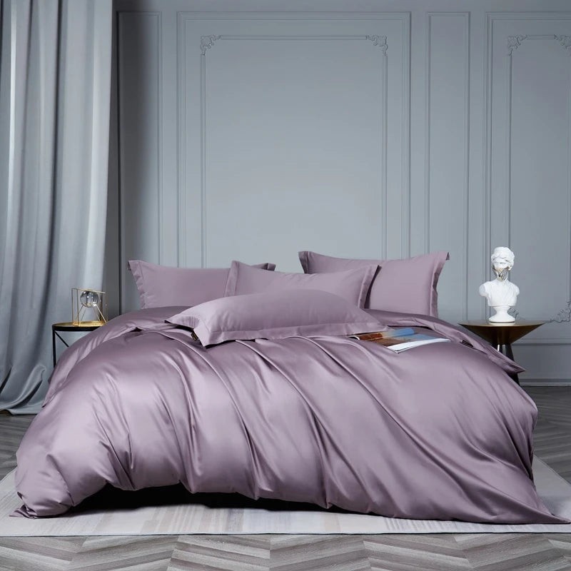 Purple bedding set on a bed in a room with gray walls and curtains.