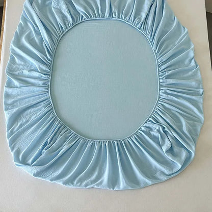 Light blue fitted sheet on a circular mattress cover against a neutral background