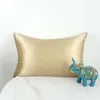Gold satin pillow on a bed with a blue elephant decoration.