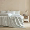 Bedding set with a white comforter and pillows on a bed in a bedroom setting.