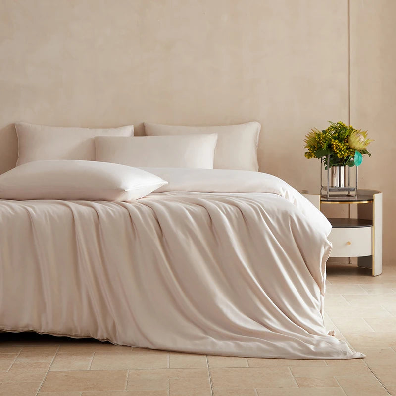 Neatly made bed with beige bedding in a bedroom setting.