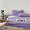 Bedding set with purple comforter and white pillows on a bed.