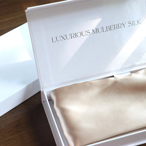 Silk scarf in a white box labeled 'Luxurious Mulberry Silk' on a wooden surface.