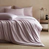 White comforter on a bed with a blurred background