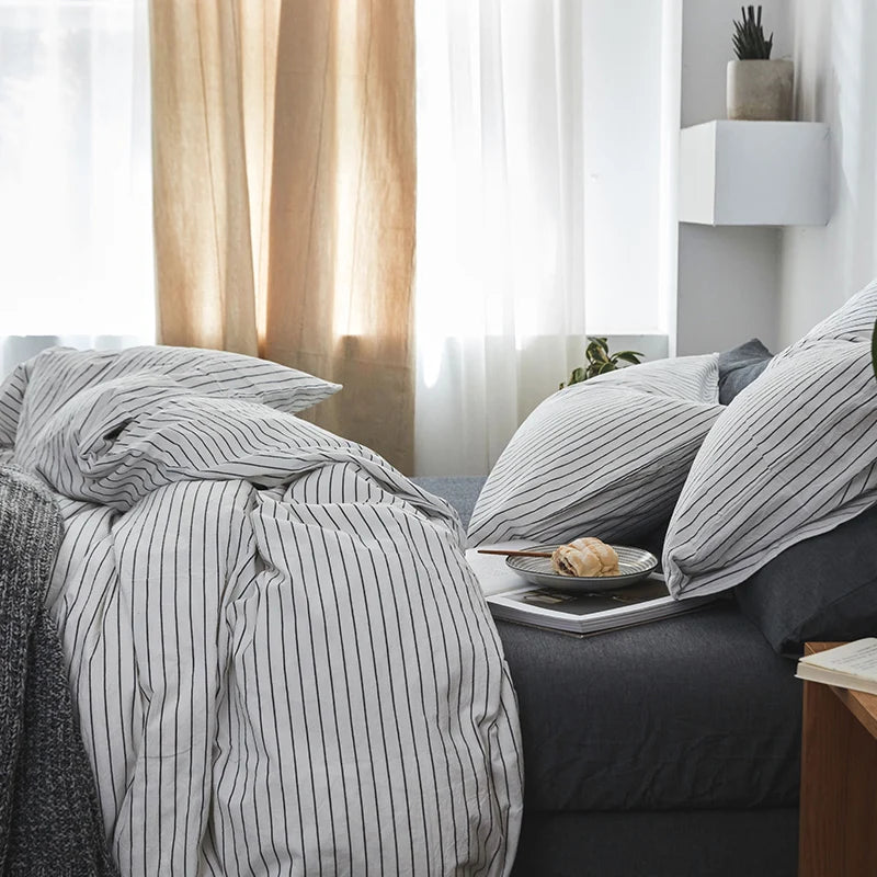 Bed with striped bedding and a tray with a snack on a nightstand.
