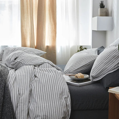 Bed with striped bedding and a tray with a snack on a nightstand.