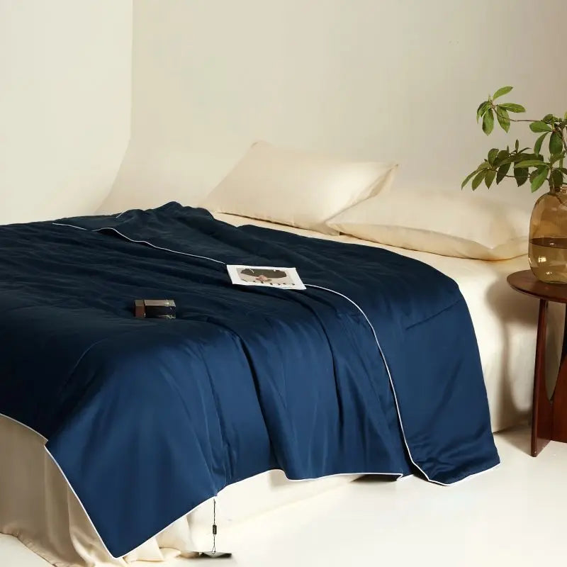 Blue blanket on a bed with a neutral background