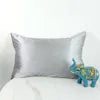 Silver pillow on a white couch with a small blue toy elephant.