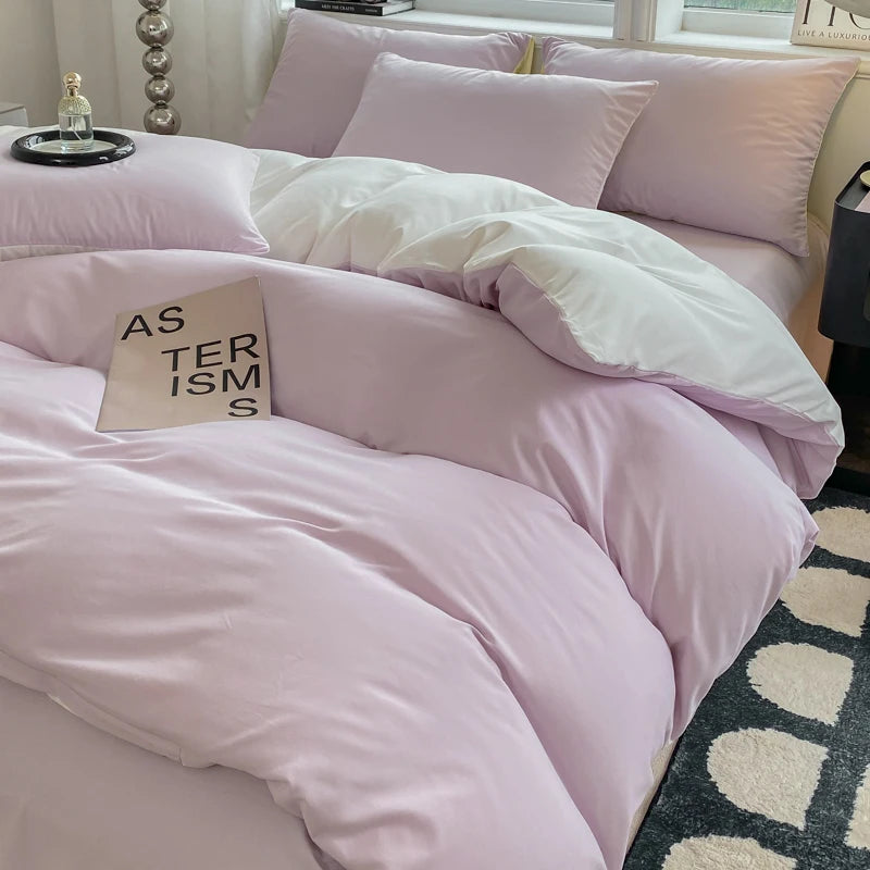 Pink bedding set on a bed with a book titled 'AS TERRORISM' on a nightstand.