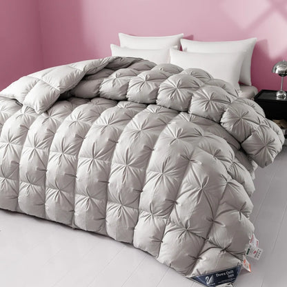 Gray quilted comforter on a bed with white pillows against a pink wall.
