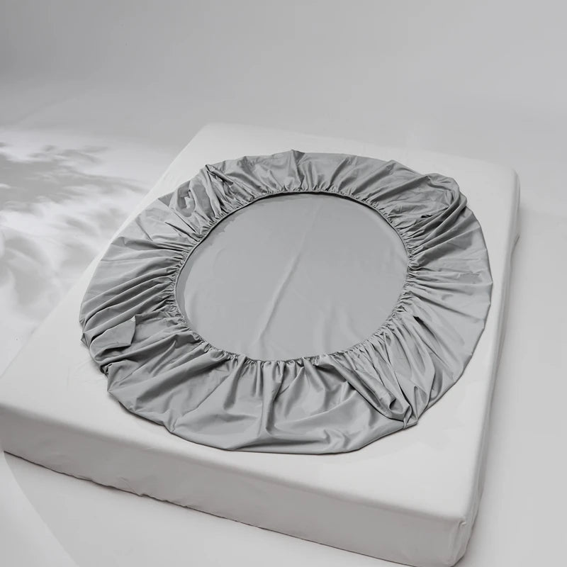 Gray fitted sheet on a mattress against a white background