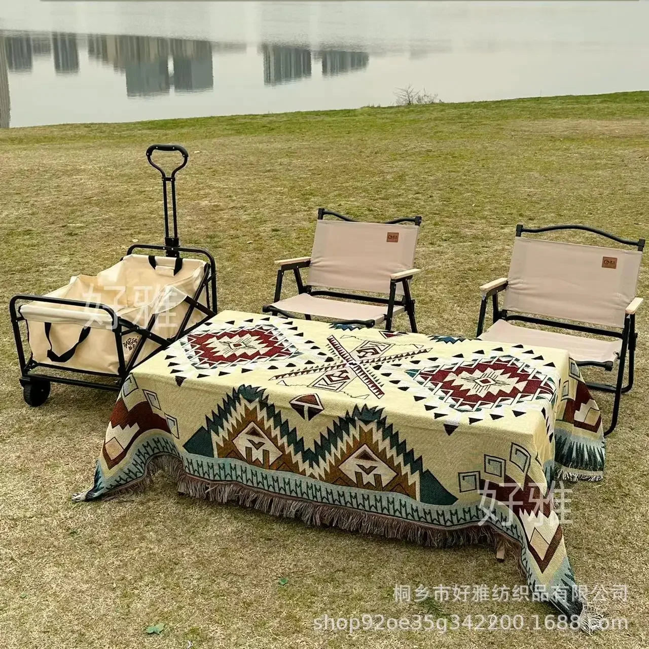 Outdoor setting with chairs, table, and trolley by a lake