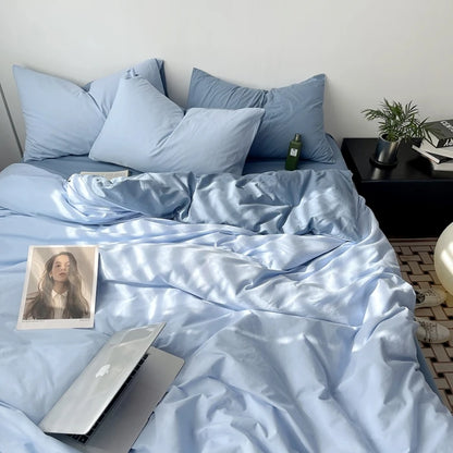 Blue bedding set with a laptop and photo on a bed in a bedroom.