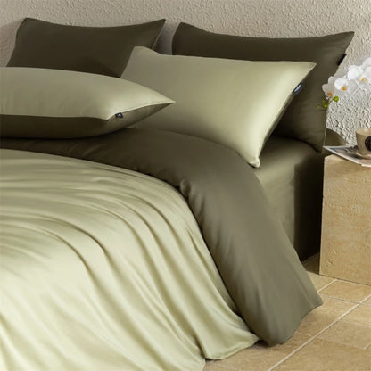 Green bedding set with pillows on a bed in a bedroom setting.