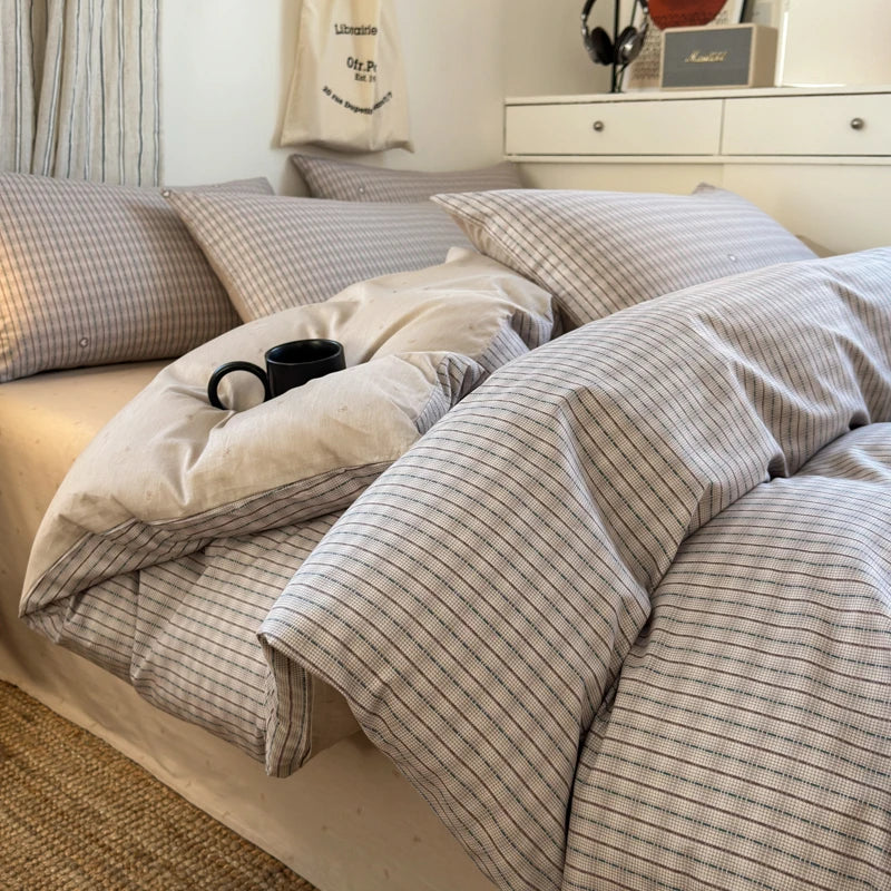 Neatly made bed with striped bedding and pillows in a bedroom setting.