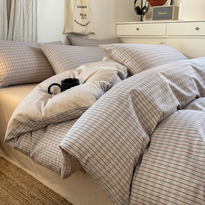 Neatly made bed with striped bedding and pillows in a bedroom setting.