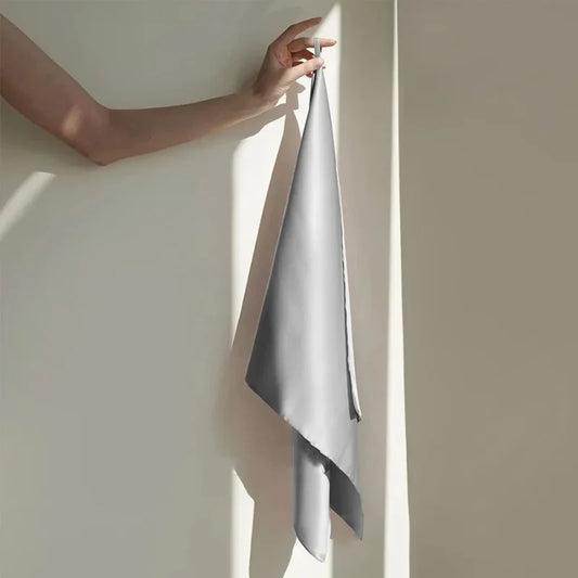 Person holding a gray towel against a neutral wall