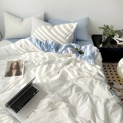 Bed with white comforter and pillows, laptop, and photo on a nightstand.