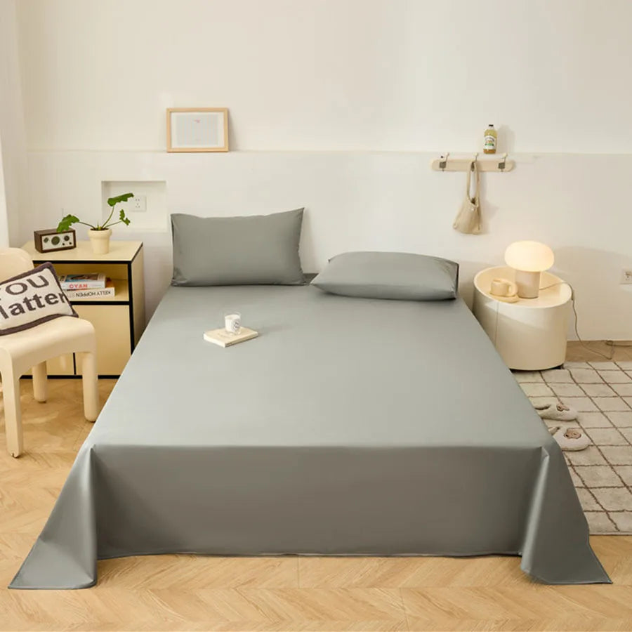 Gray bedspread on a bed in a bedroom setting with nightstands and decor.