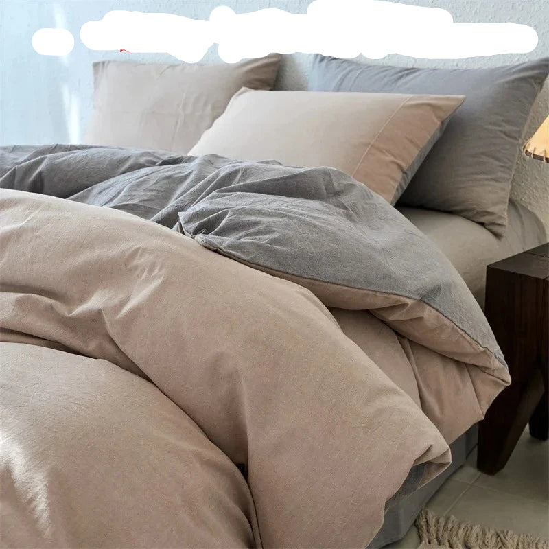 Neatly made bed with beige and gray bedding, nightstand on the side.