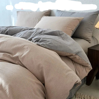 Neatly made bed with beige and gray bedding, nightstand on the side.