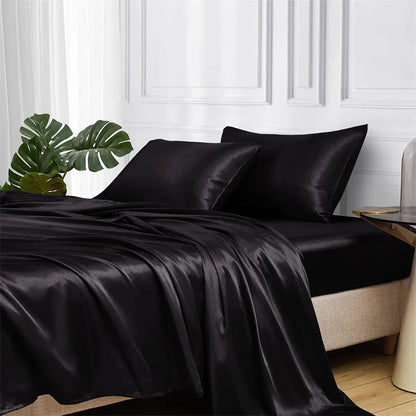 Black satin bedding set on a bed with a white wall and plant in the background