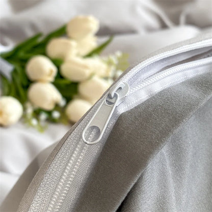 Close-up of a silver zipper on a gray fabric with white tulips in the background.