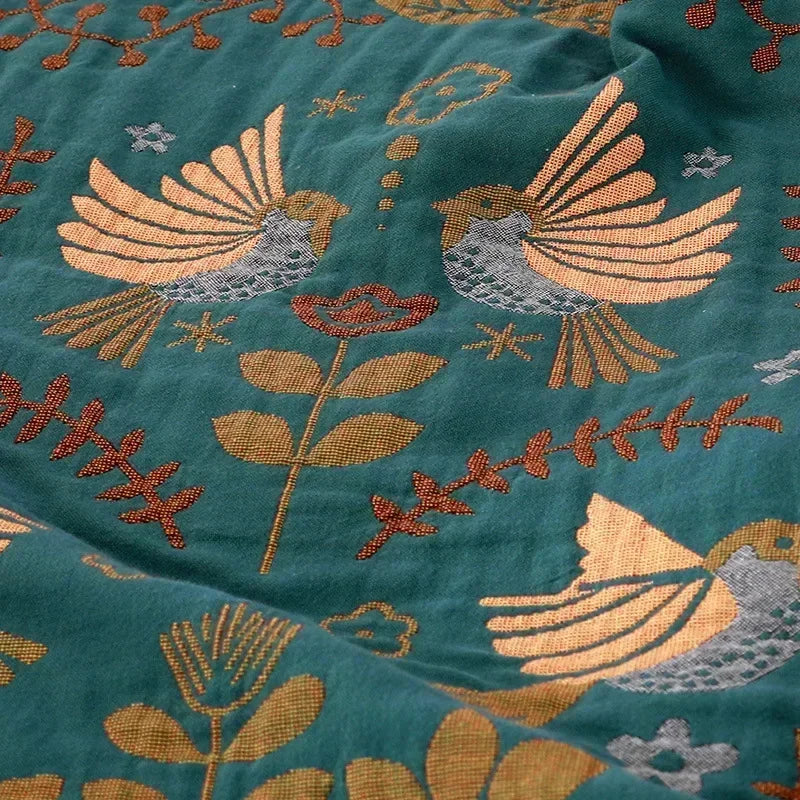 Embroidered fabric with birds and floral patterns on a teal background