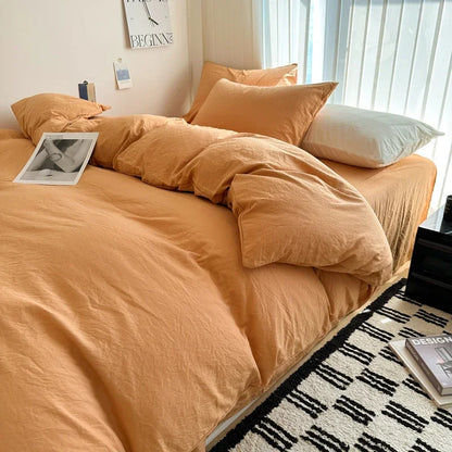 Bed with orange bedding and pillows in a room with a window and decor.