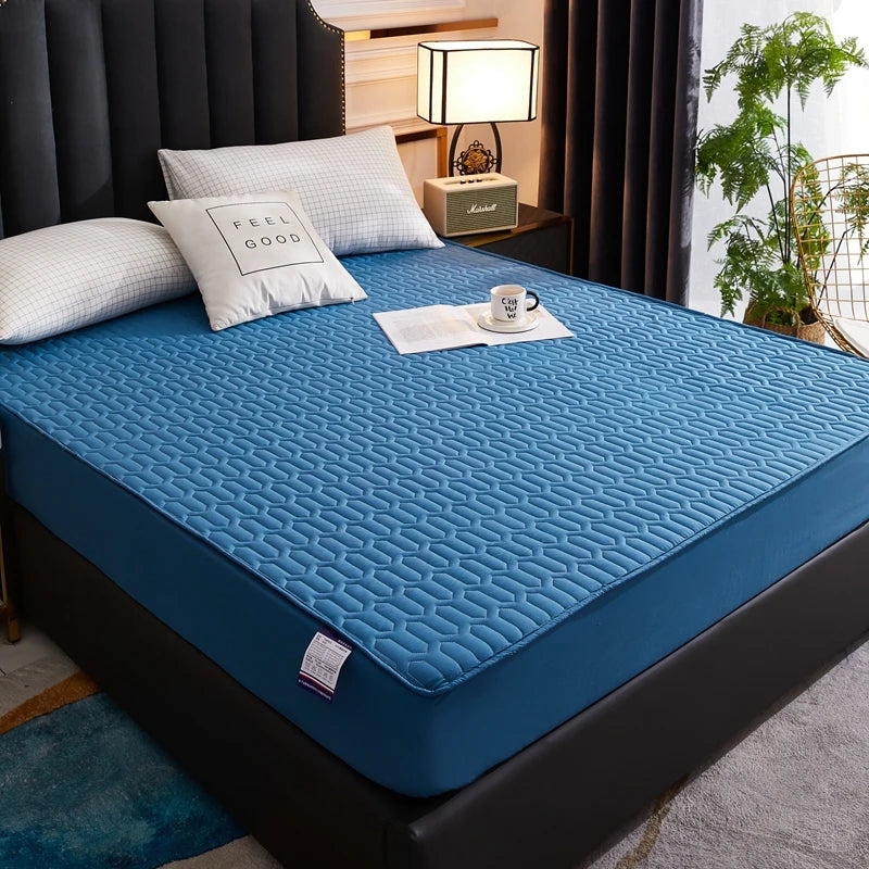 Blue mattress cover on a bed with pillows and a lamp in a bedroom setting